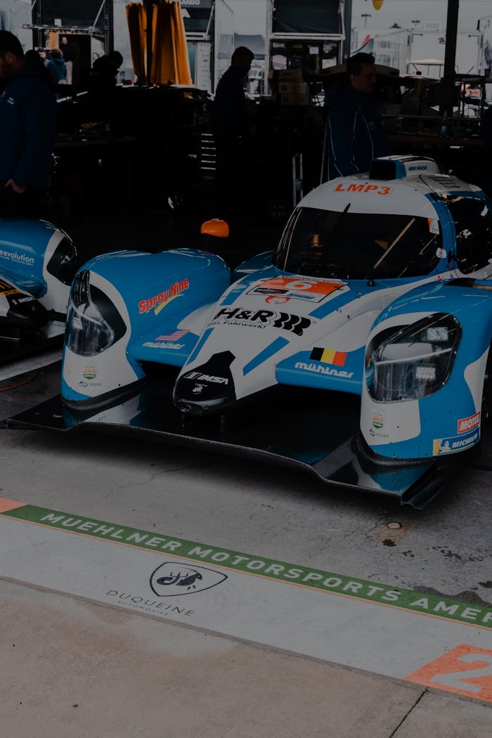High-performance LMP3 racing car parked in a garage at a motorsport event.